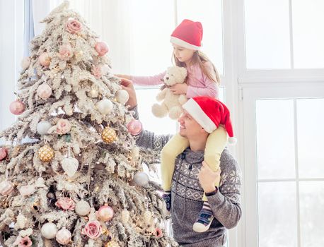 Father holding daughter near christmas tree