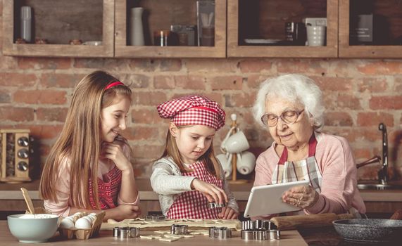 Grandma with granddaughters looking for a recipe in tablet