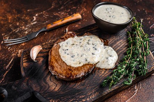 Grilled sirloin beef meat steak with peppercorn sauce. Dark background. Top view