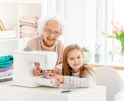 Grandmother teaching grandkid to sew