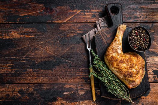 Grilled chicken leg on a wooden board. Dark wooden background. Top view. Copy space
