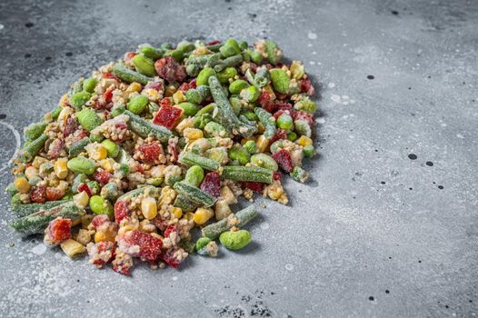 Assortment of frozen vegetables and quinoa with ice. Gray background. Top view. Copy space