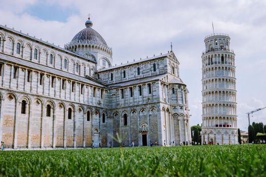 Leaning tower of Pisa, Italy with Basilica and Cathedral on a bright summer day with green gras low angle