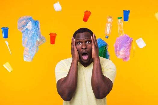 World Environment Day, plastic recycling problem and environmental disaster concept - Terrified man on yellow background with trash