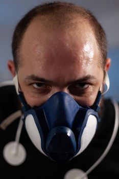 Portrait of runner man wearing mask looking into camera while working at body endurance