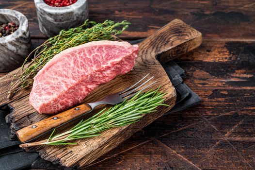 Wagyu A5 raw rump or sirloin steak, kobe beef meat on a butchery board. Dark wooden background. Top view. Copy space