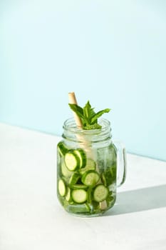Homemade refreshing water with mint and cucumber in a mason jar with hard light and shadows