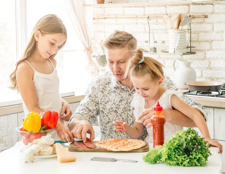 dad with daughters preparing pizza