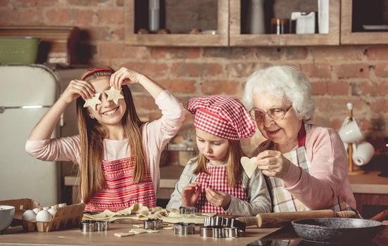 Grandma teaching granddaughters to bake cookies