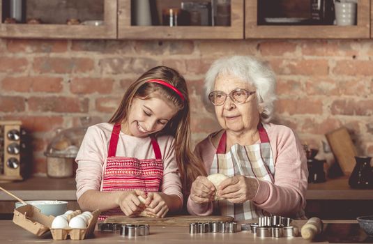 Elderly woman teaching a little girl to bake cookies
