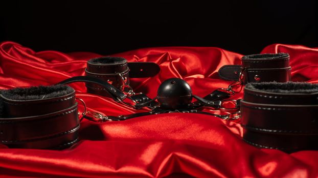 Bdsm outfit. Bondage and Gag ball on the red linen. Adult sex games. Kinky lifestyle.