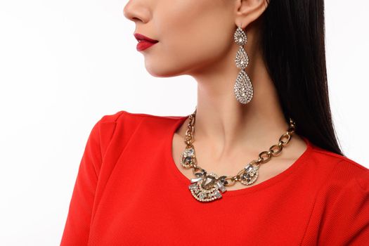Profile of a beautiful woman in red evening dress with necklace and earrings