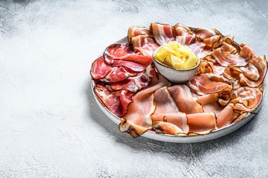 Meat antipasto platter, pancetta, salami, sliced ham, sausage, prosciutto, bacon. Gray background. Top view. Copy space