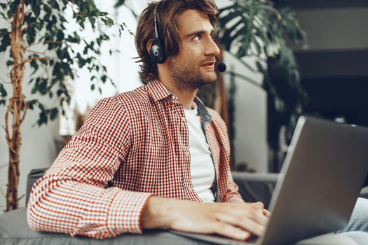 Young man wearing headset doing a video call by laptop