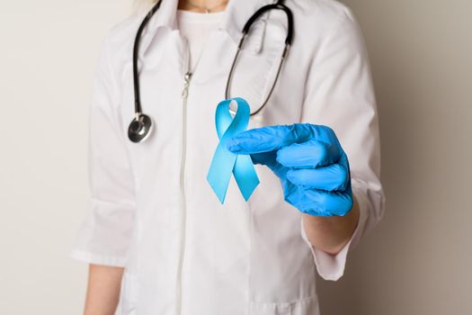 Female doctor holding a blue ribbon in her hands