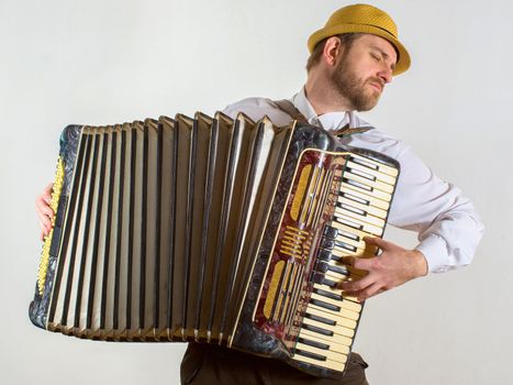 Portrait of a man in straw hat playing on accordion