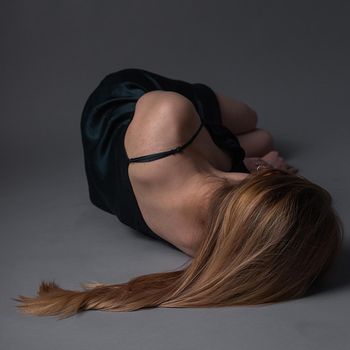 girl in dress lies on floor with head turned away. Depression, anxiety concept