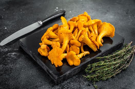 Raw wild Chanterelles mushrooms on a marble board. Black background. Top view