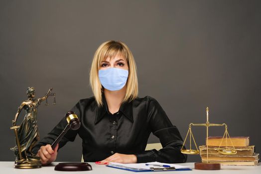 A young fair woman judge in protective mask works in her office.