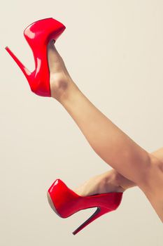 Perfect female legs wearing red high heels isolated on white background