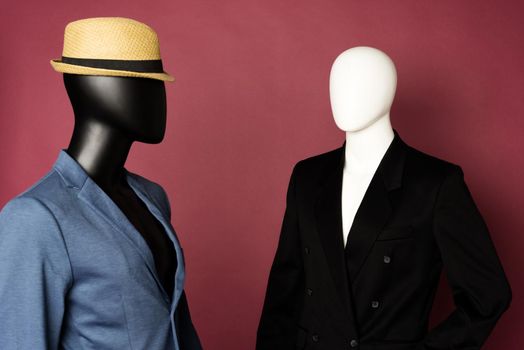 Two male mannequin in a black business suit and in a blue suit and white pants on a ruby background