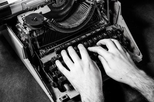 Hands writing on old typewriter