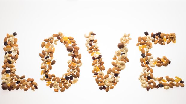 The word love laid out from a mix of nuts on a white background.