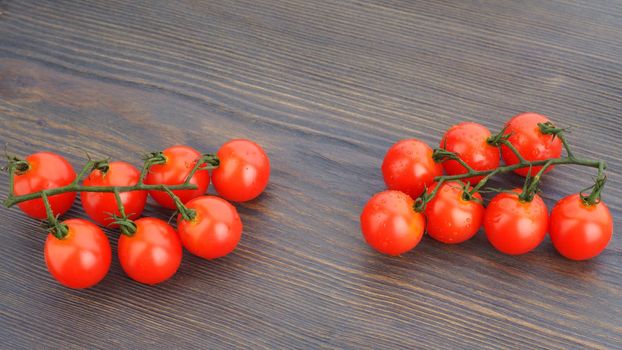 Ripe cherry tomatoes on a twig on a dark woden background