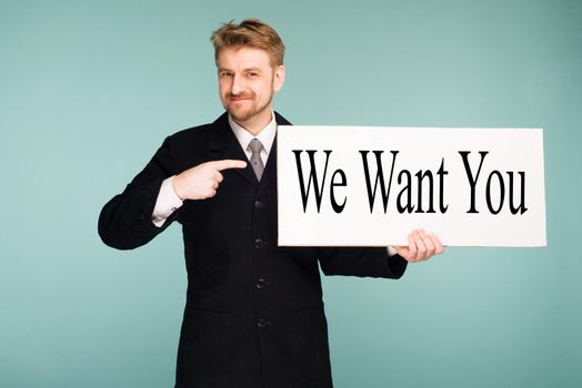 Happy smiling young business man points finger signboard with sign We Want You