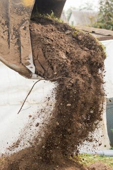A bulldozer pours out a bucket of land on a construction site close-up. Excavation industrial work
