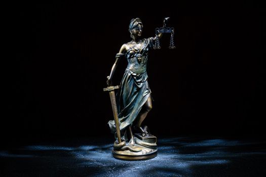 Themis statuette stands on the old vintage stone table.