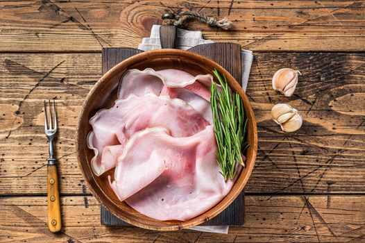 Sliced Prosciutto ham in a wooden plate. wooden background. Top view