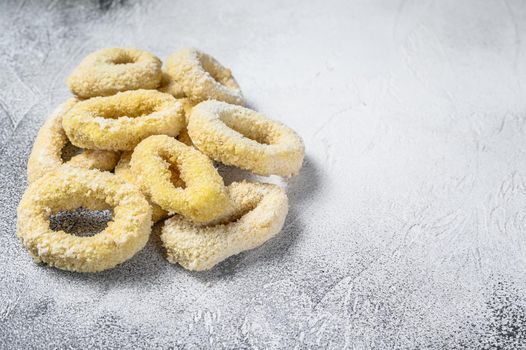Frozen raw squid rings in breadcrumbs. White background. Top view. Copy space
