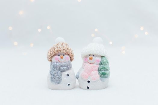 Decorative Christmas-themed figurines. Two statuette of a snowmen in a knitted hat on the white background.