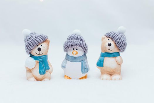 Decorative Christmas-themed figurines. The statuette of a cat, penguin and a bear in a knitted hat on the white background.