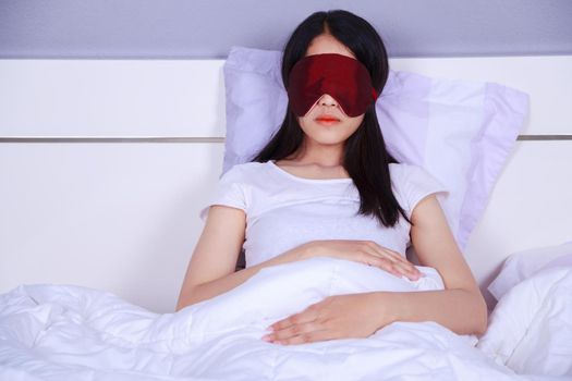 woman sleeping with eye mask on bed in bedroom