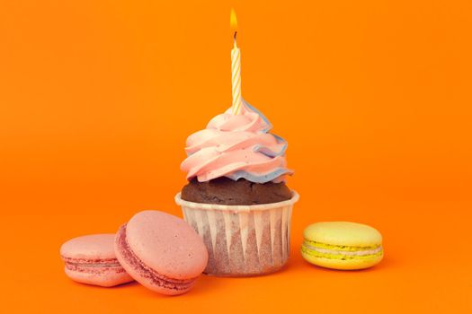 Cupcake with birthday candles on orange background