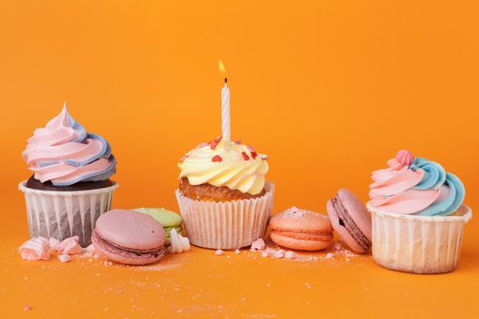Cupcake with birthday candles on orange background