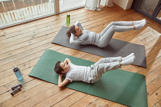 Active woman doing workout with son indoors