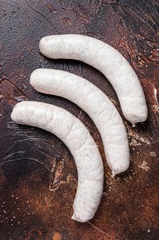 Raw German white sausage weisswurst on kitchen table. Dark background. Top view