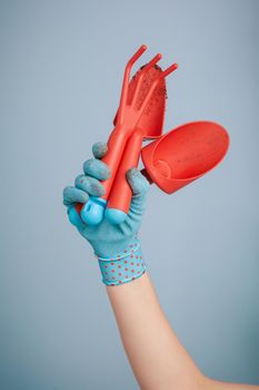 Hand holding garden tools on blue background