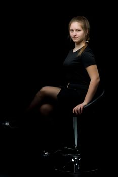 Charming girl teenager sitting on a chair in the studio