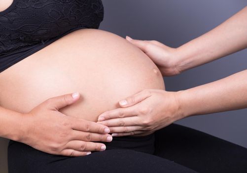 hand touching belly of pregnant woman 