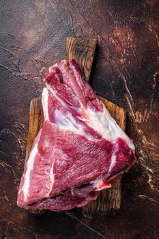 Raw lamb mutton thigh on butcher table. Dark background. Top view
