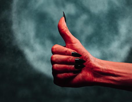 Devil hand with thumb up gesture at midnight