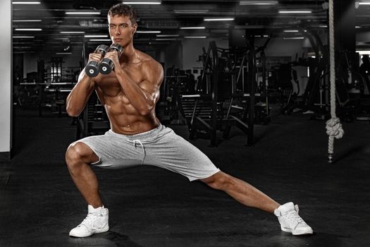 Muscular man athlete in fitness gym have havy workout. Fitness sports trainer on trainging with dumbbells. Full body workout.