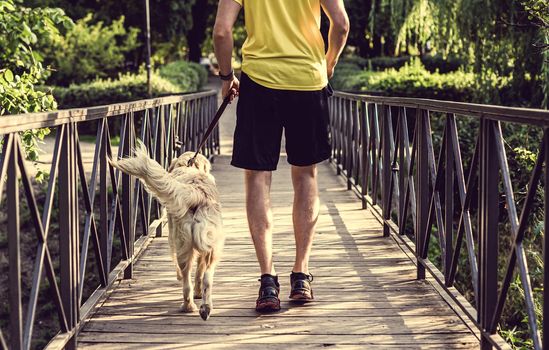 Man jogging across bridge with dog
