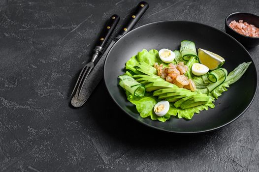Fresh seafood salad with grilled shrimps prawns, egg, avocado and cucumber in a plate. Black background. top view. Copy space