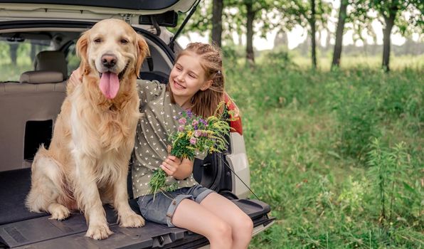 Preteen girl with golden retriever dog in the car