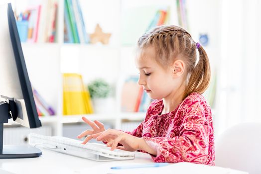 Little girl typing on computer keyboard